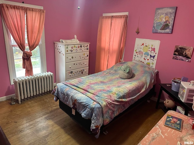 bedroom with dark hardwood / wood-style floors and radiator