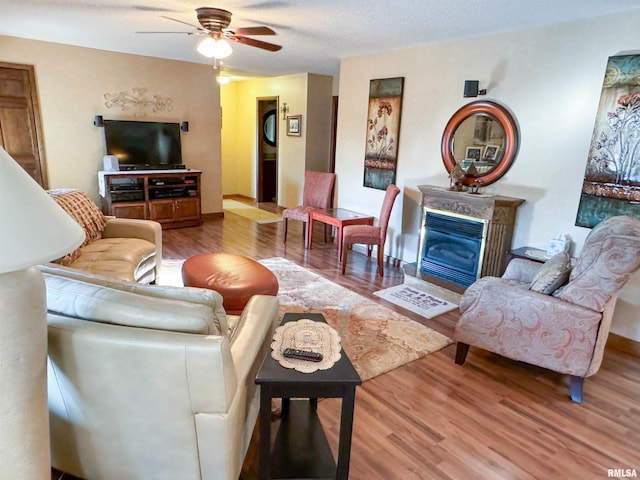 living room featuring ceiling fan, hardwood / wood-style flooring, and a fireplace