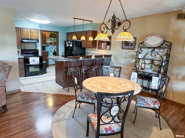 dining area featuring light hardwood / wood-style flooring and a textured ceiling