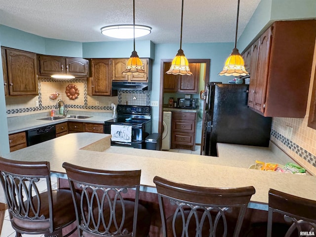 kitchen with decorative backsplash, kitchen peninsula, sink, black appliances, and a breakfast bar