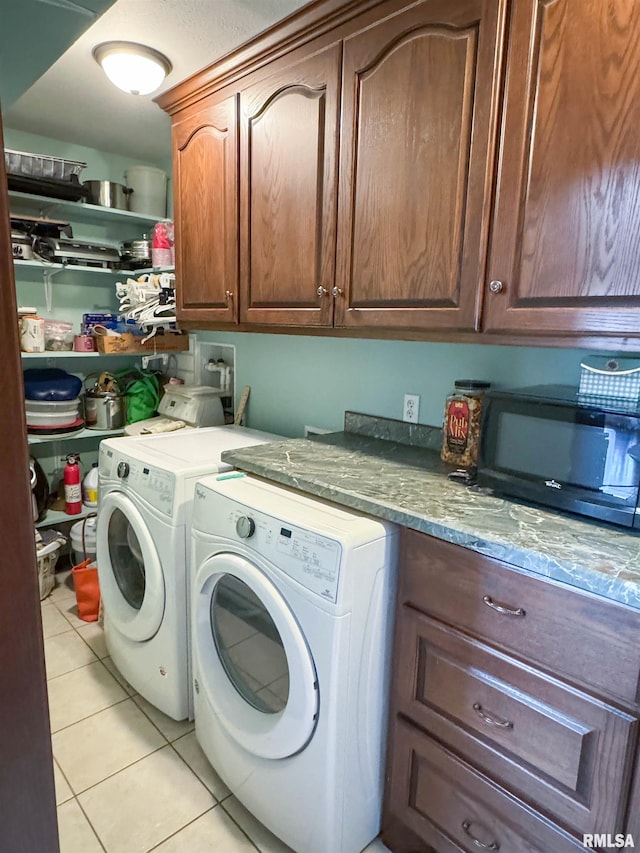 laundry area featuring cabinets, washer and dryer, and light tile patterned floors