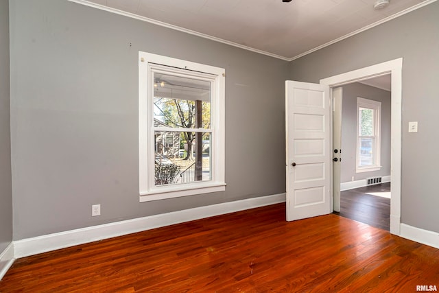 empty room with crown molding, wood-type flooring, and a healthy amount of sunlight