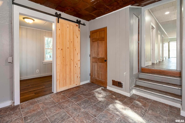 interior space with wooden walls, a barn door, dark wood-type flooring, and wooden ceiling