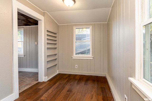 unfurnished room featuring wooden walls, dark wood-type flooring, and vaulted ceiling