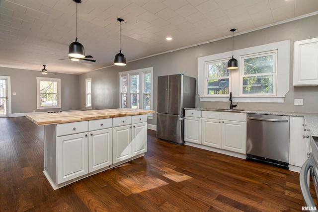 kitchen with appliances with stainless steel finishes, white cabinets, and butcher block counters