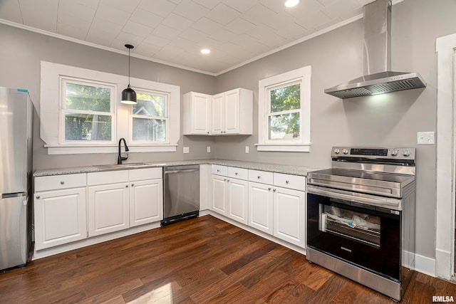 kitchen with a healthy amount of sunlight, stainless steel appliances, wall chimney range hood, and white cabinetry