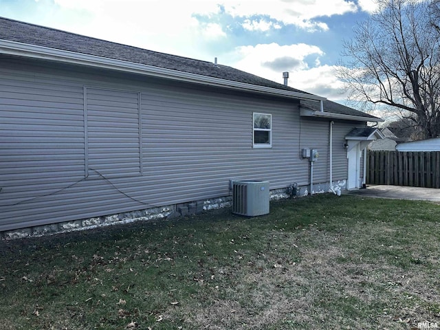 view of side of home with a yard and central AC