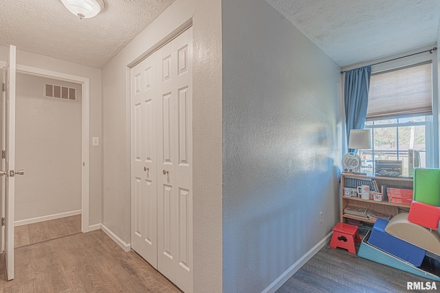 corridor featuring light hardwood / wood-style floors and a textured ceiling