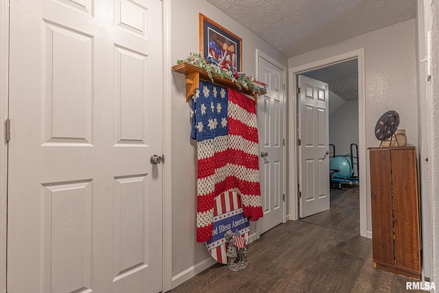 hallway with a textured ceiling and dark hardwood / wood-style flooring