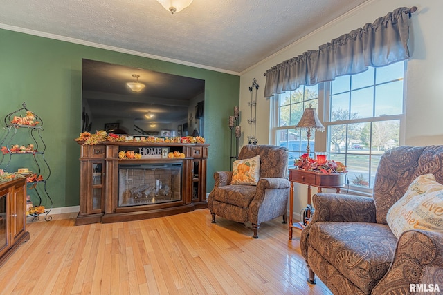 sitting room with ornamental molding, a textured ceiling, and light hardwood / wood-style floors