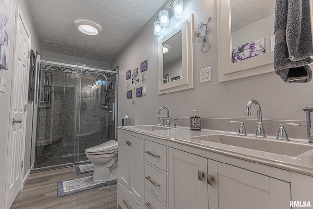 bathroom with hardwood / wood-style flooring, toilet, vanity, a textured ceiling, and walk in shower