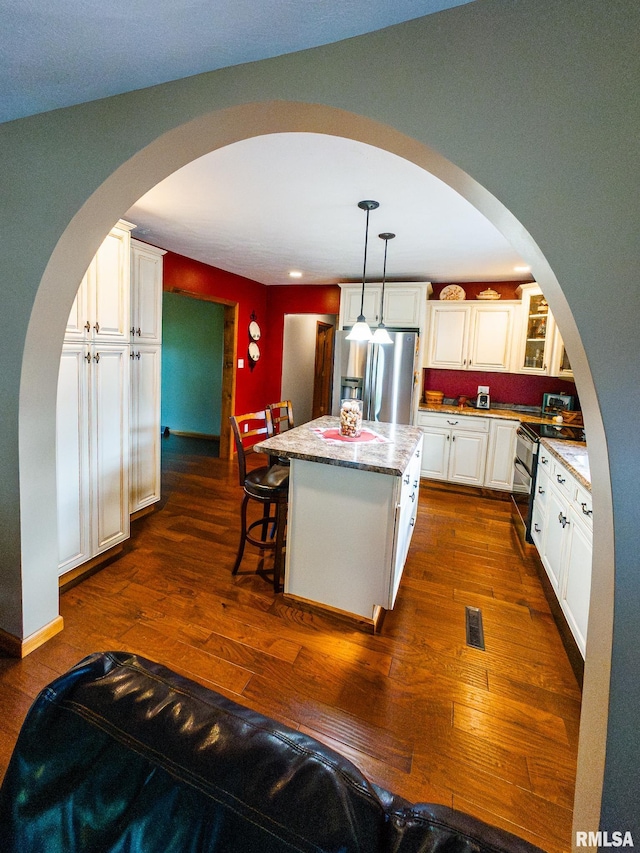 kitchen featuring dark hardwood / wood-style flooring, white cabinets, a center island, and pendant lighting