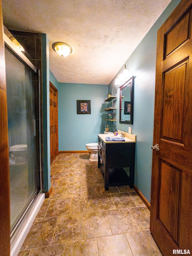 bathroom with vanity, a shower with shower door, a textured ceiling, and toilet