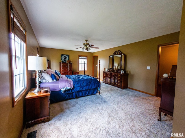 carpeted bedroom featuring ceiling fan and multiple windows