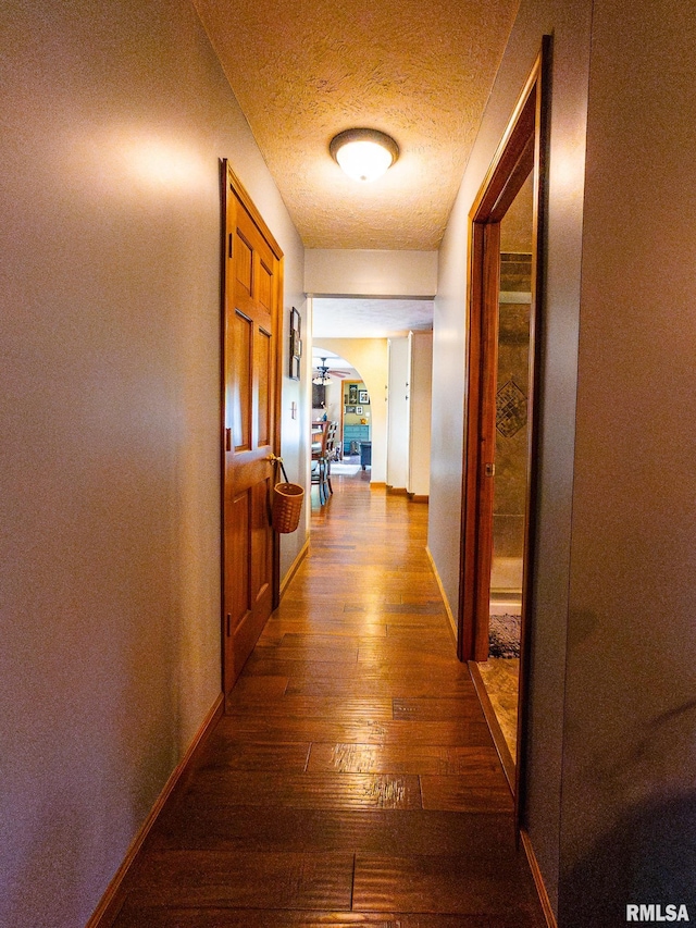 hallway featuring a textured ceiling and dark hardwood / wood-style floors