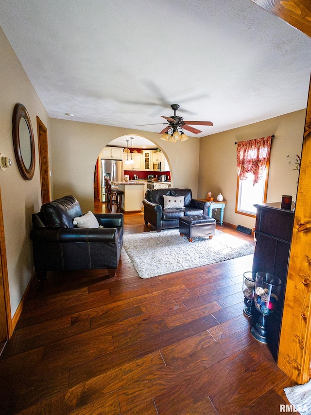 living room with dark hardwood / wood-style floors, a textured ceiling, and ceiling fan