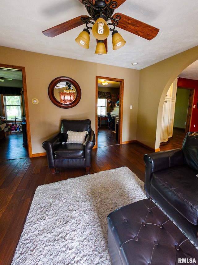 living room with ceiling fan and dark hardwood / wood-style flooring