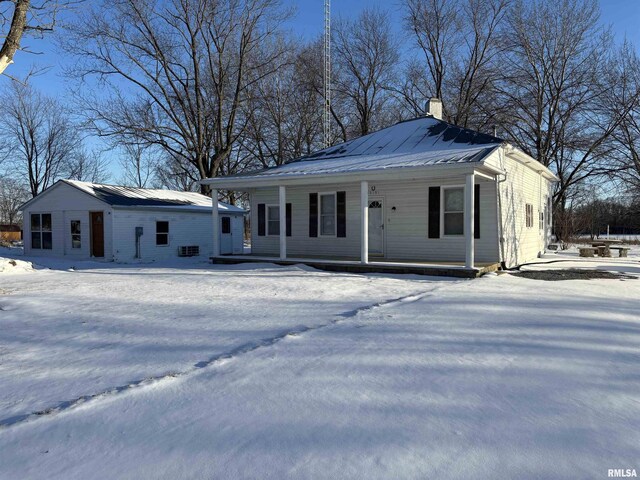 view of front of home featuring covered porch, a garage, and an outbuilding