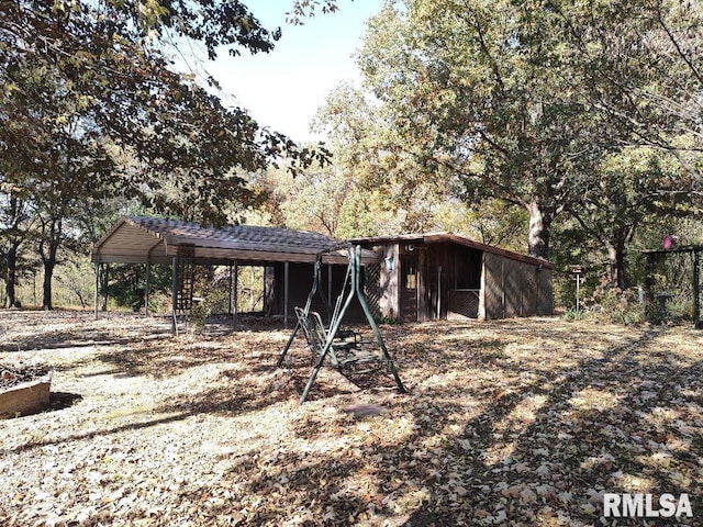 view of front of property featuring a carport and an outbuilding