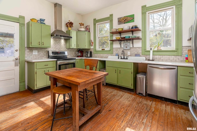 kitchen with wall chimney exhaust hood, appliances with stainless steel finishes, light hardwood / wood-style flooring, and decorative backsplash