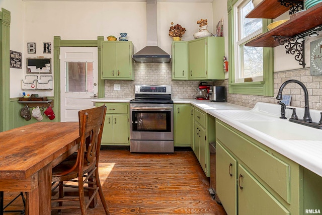 kitchen featuring wall chimney range hood, stainless steel range with electric stovetop, green cabinets, and dark hardwood / wood-style flooring