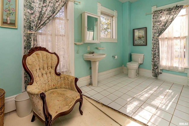 bathroom with toilet, sink, and tile patterned floors