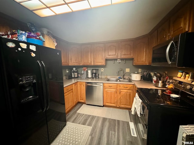 kitchen with sink, black appliances, and light hardwood / wood-style floors