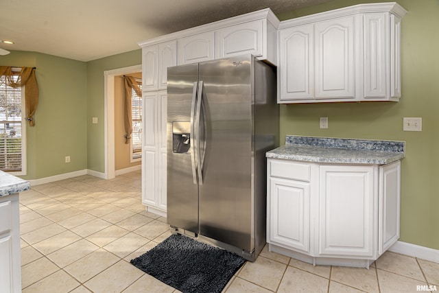 kitchen featuring light tile patterned flooring, stainless steel fridge with ice dispenser, and white cabinets