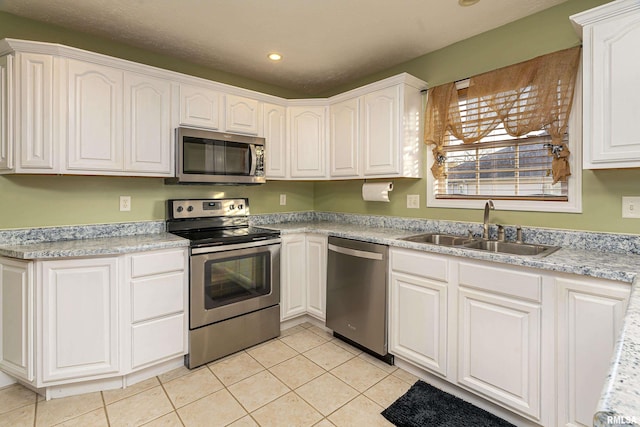 kitchen featuring stainless steel appliances, sink, light tile patterned floors, and white cabinets