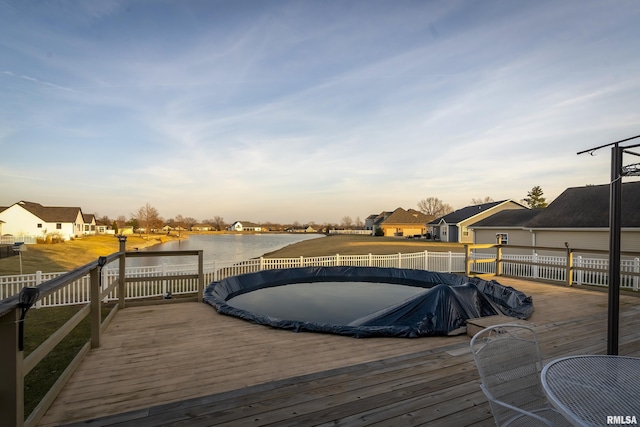 deck at dusk featuring a water view