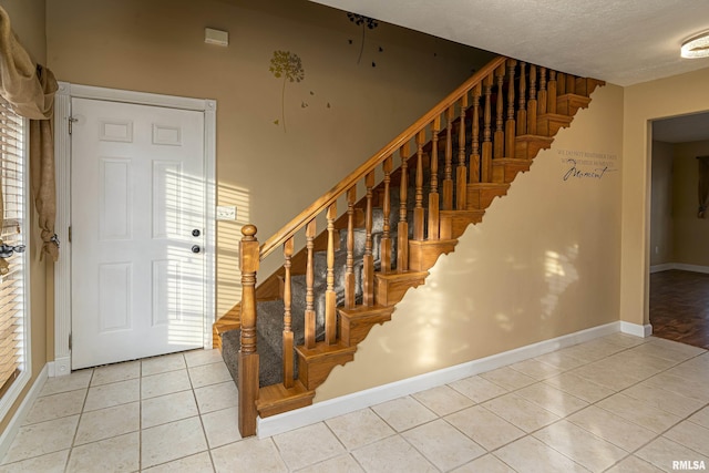 stairs featuring plenty of natural light, tile patterned floors, and a textured ceiling