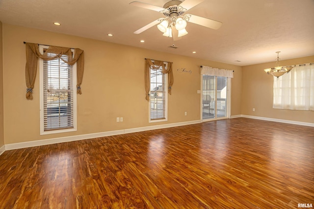 spare room featuring wood-type flooring and ceiling fan with notable chandelier