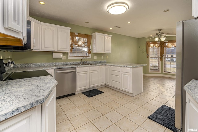 kitchen with sink, white cabinets, light tile patterned floors, kitchen peninsula, and stainless steel appliances