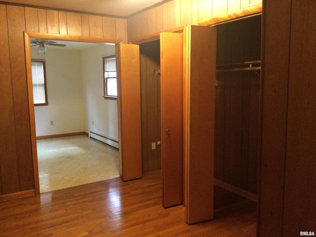 interior space featuring a baseboard heating unit, hardwood / wood-style flooring, and wood walls