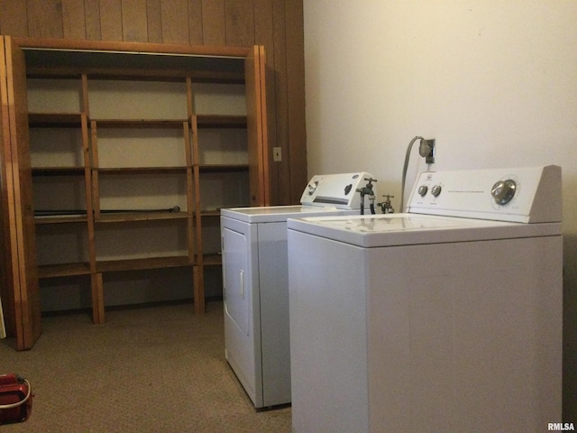 laundry room featuring light colored carpet, wood walls, and washing machine and clothes dryer