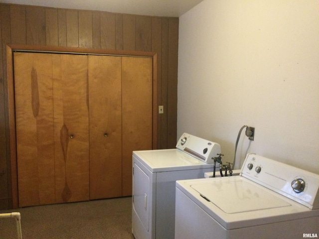 clothes washing area with wooden walls and separate washer and dryer