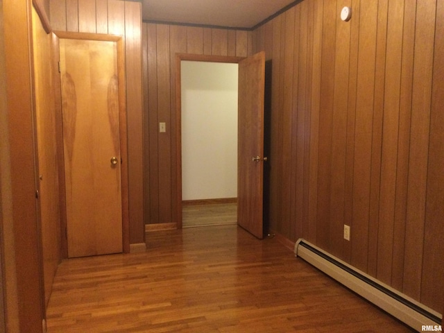 hall featuring a baseboard radiator, hardwood / wood-style floors, and wooden walls