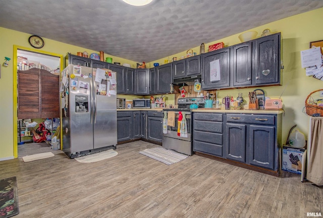 kitchen featuring light hardwood / wood-style floors, a textured ceiling, and stainless steel appliances