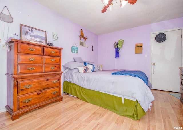 bedroom featuring ceiling fan, light hardwood / wood-style flooring, and a textured ceiling