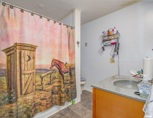 bathroom with a textured ceiling, toilet, and vanity