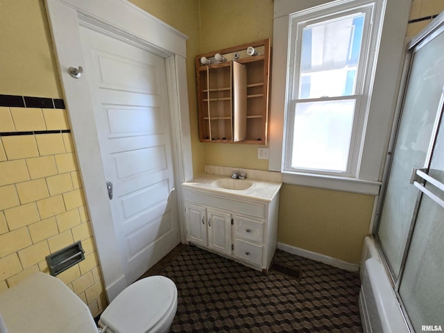 full bathroom with toilet, a wealth of natural light, vanity, and shower / bath combination with glass door