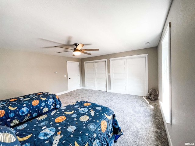 carpeted bedroom with ceiling fan and two closets