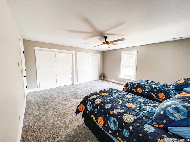 carpeted bedroom with ceiling fan and two closets