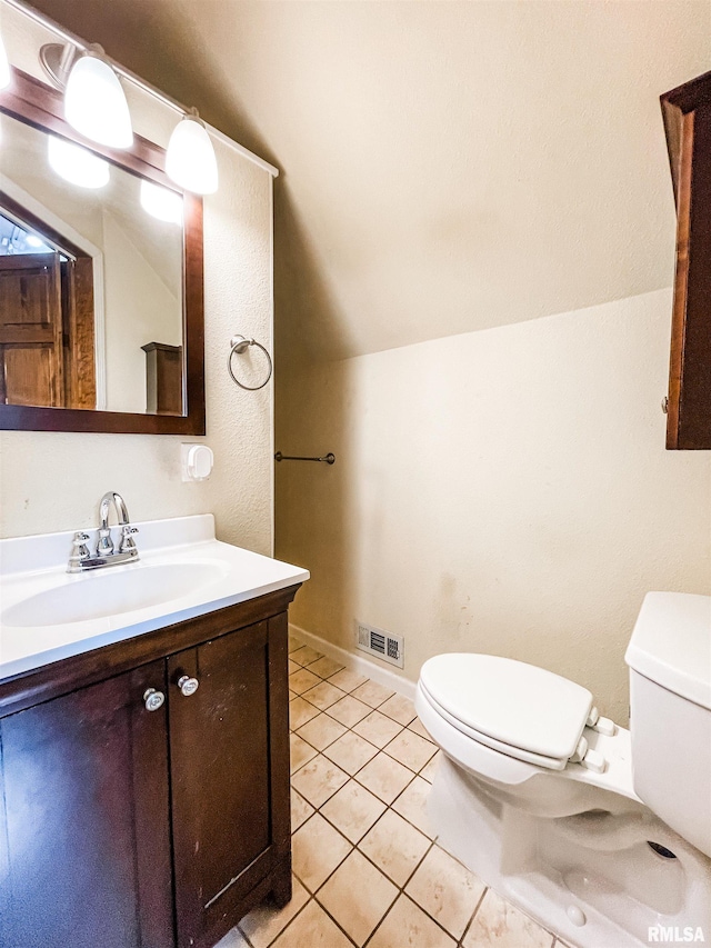 bathroom with toilet, vanity, vaulted ceiling, and tile patterned flooring