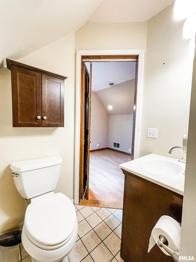 bathroom with toilet, vanity, lofted ceiling, and hardwood / wood-style floors