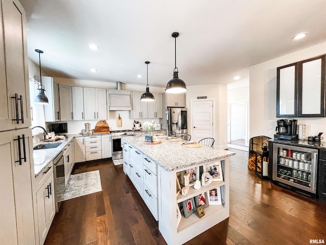 kitchen featuring appliances with stainless steel finishes, light stone countertops, decorative light fixtures, a kitchen island, and dark wood-type flooring