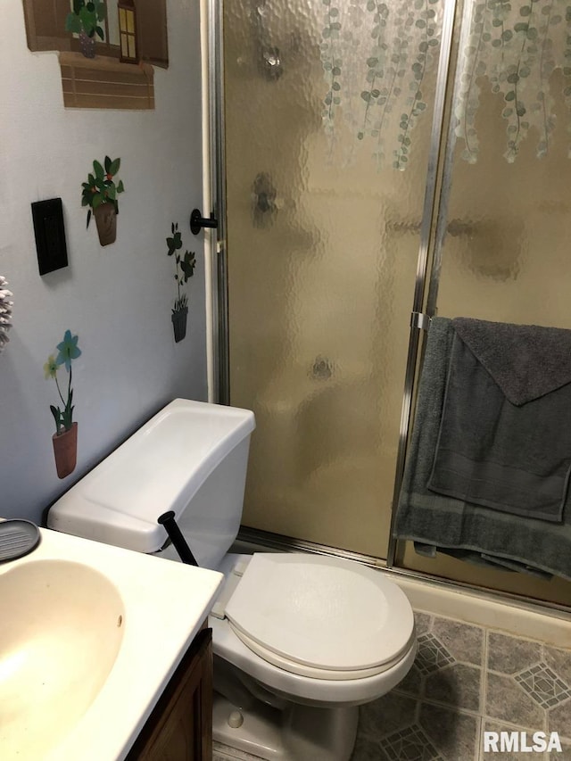 bathroom with a shower with door, vanity, toilet, and tile patterned flooring