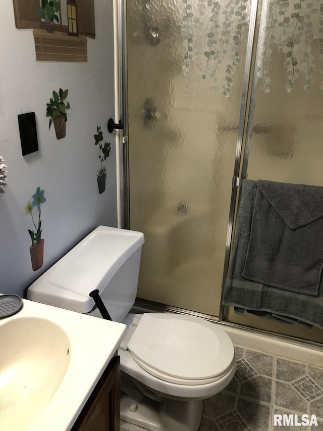 bathroom featuring a shower with door, vanity, tile patterned flooring, and toilet