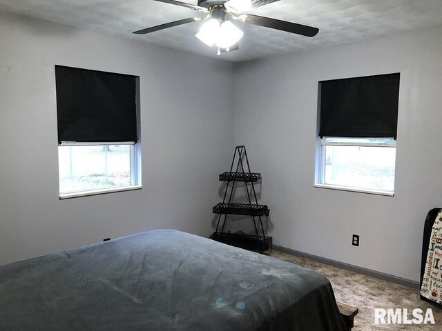 carpeted bedroom featuring multiple windows and ceiling fan