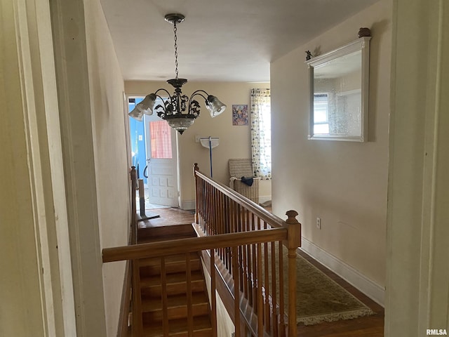 stairs featuring wood finished floors, a chandelier, and baseboards
